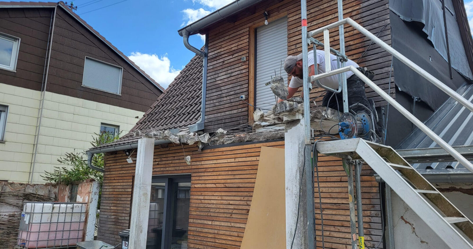 Blick auf abgerissene Garage an einem Holzhaus und Marco am Arbeiten